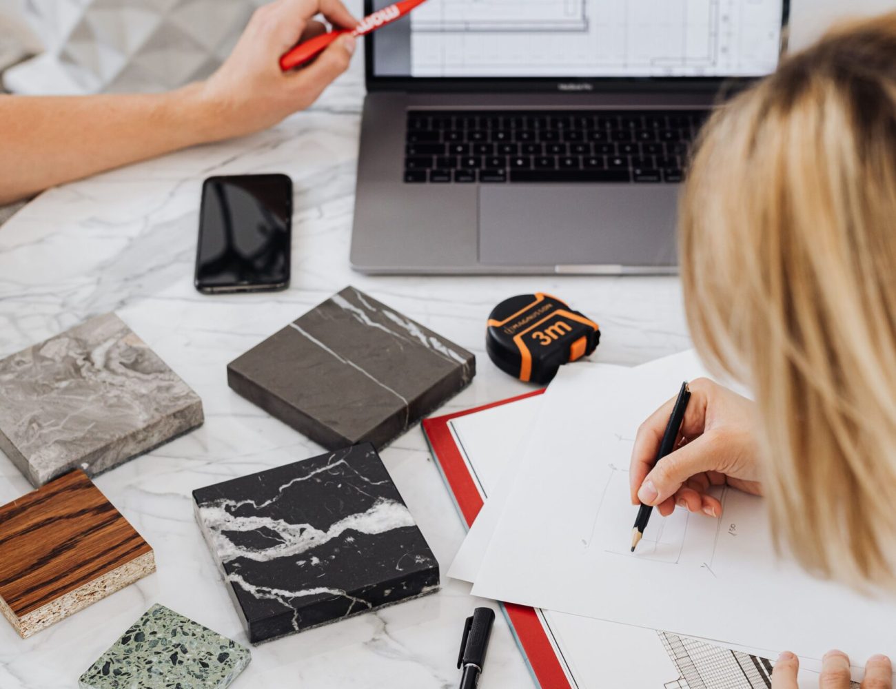 Creative professionals designing interior spaces with laptop and material samples at a modern work table.