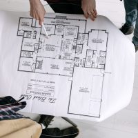 Two architects examining a detailed floor plan blueprint on a table indoors.